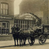 {
																																					A historical photograph of a horse-drawn funeral cortege outside the Hinckley office
																																			