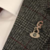 {
																																					A close-up of the silver G. Seller lapel badge
																																			